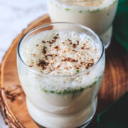 masala chaas in two glasses on a wooden round board with napkin on side