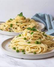 Pasta with peas and ricotta in two plates with napkin on side
