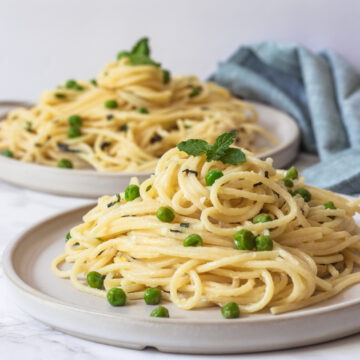 Pasta with peas and ricotta in two plates with napkin on side