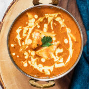 close up top view of shahi paneer in a serving wok on a wooden board