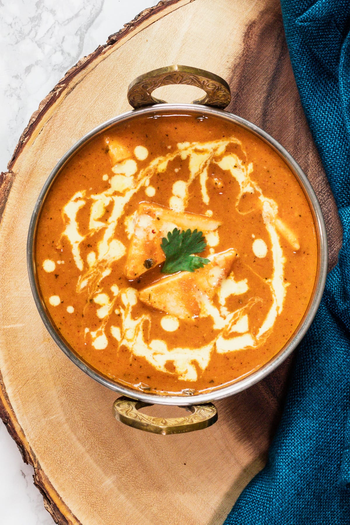 Shahi paneer in a serving wok on a wooden board