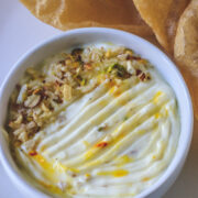close up image of shrikhand served in a bowl with a garnish of chopped nuts.