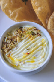 close up image of shrikhand served in a bowl with a garnish of chopped nuts.