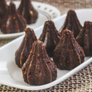 Chocolate modak arranged on rectangular plate with few in background