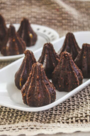 Chocolate modak arranged on rectangular plate with few in background