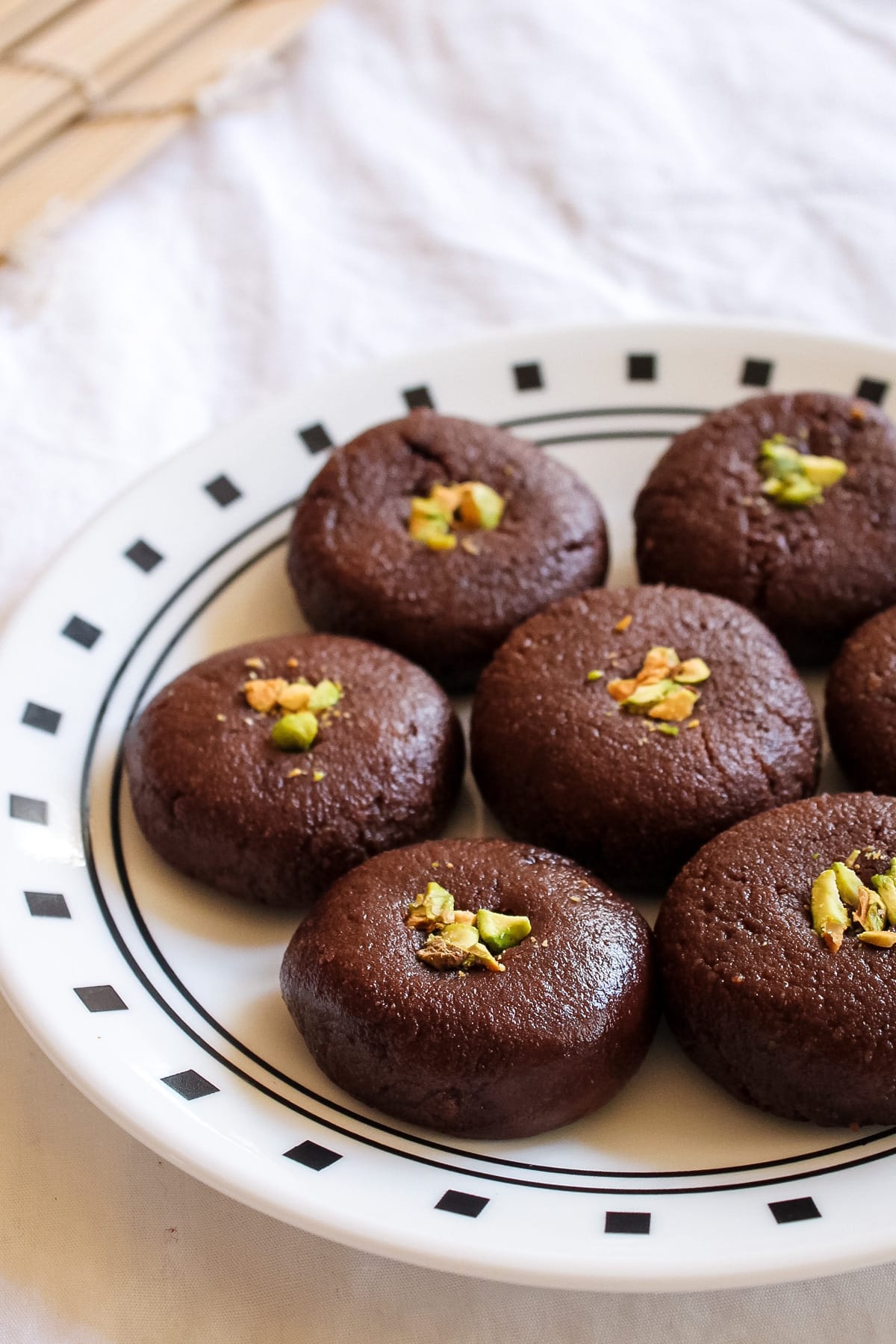 Close up of chocolate peda garnished with chopped pistachio in a plate