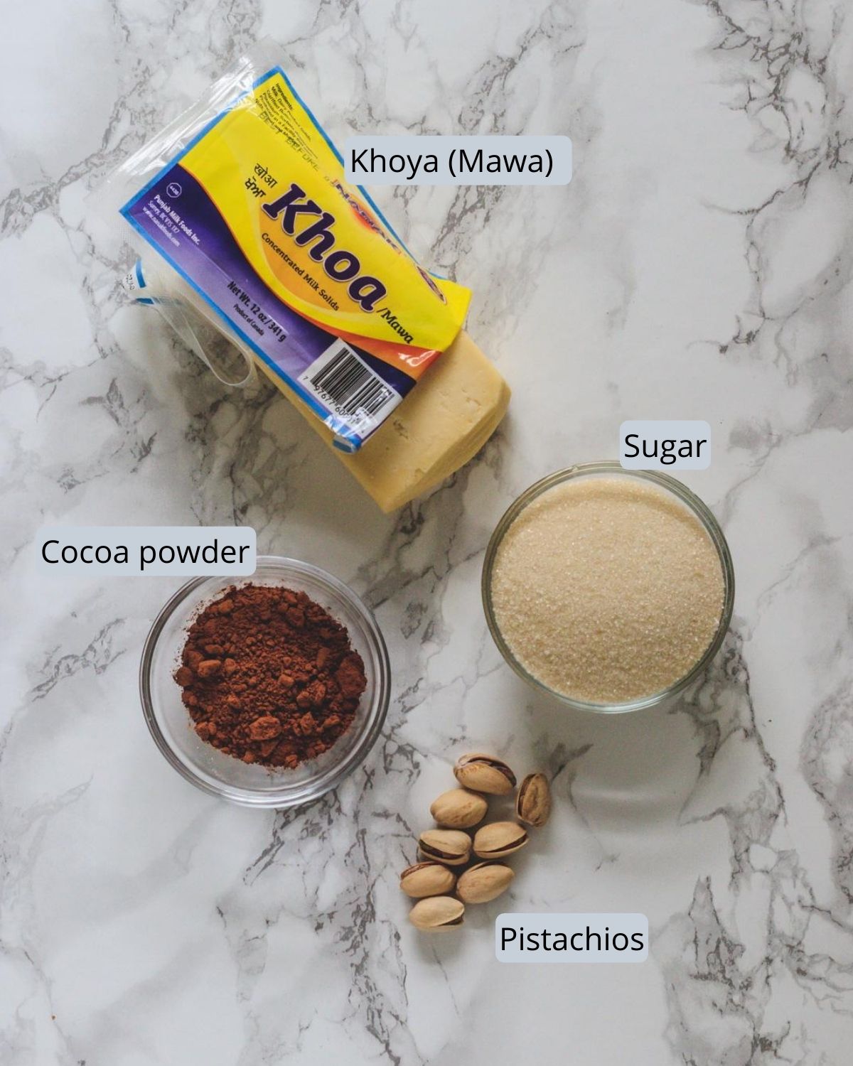 image of ingredients used in chocolate peda includes khoya, sugar, cocoa powder and pistachios