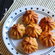 Image of fried modaks on plate with bamboo mat underneath.