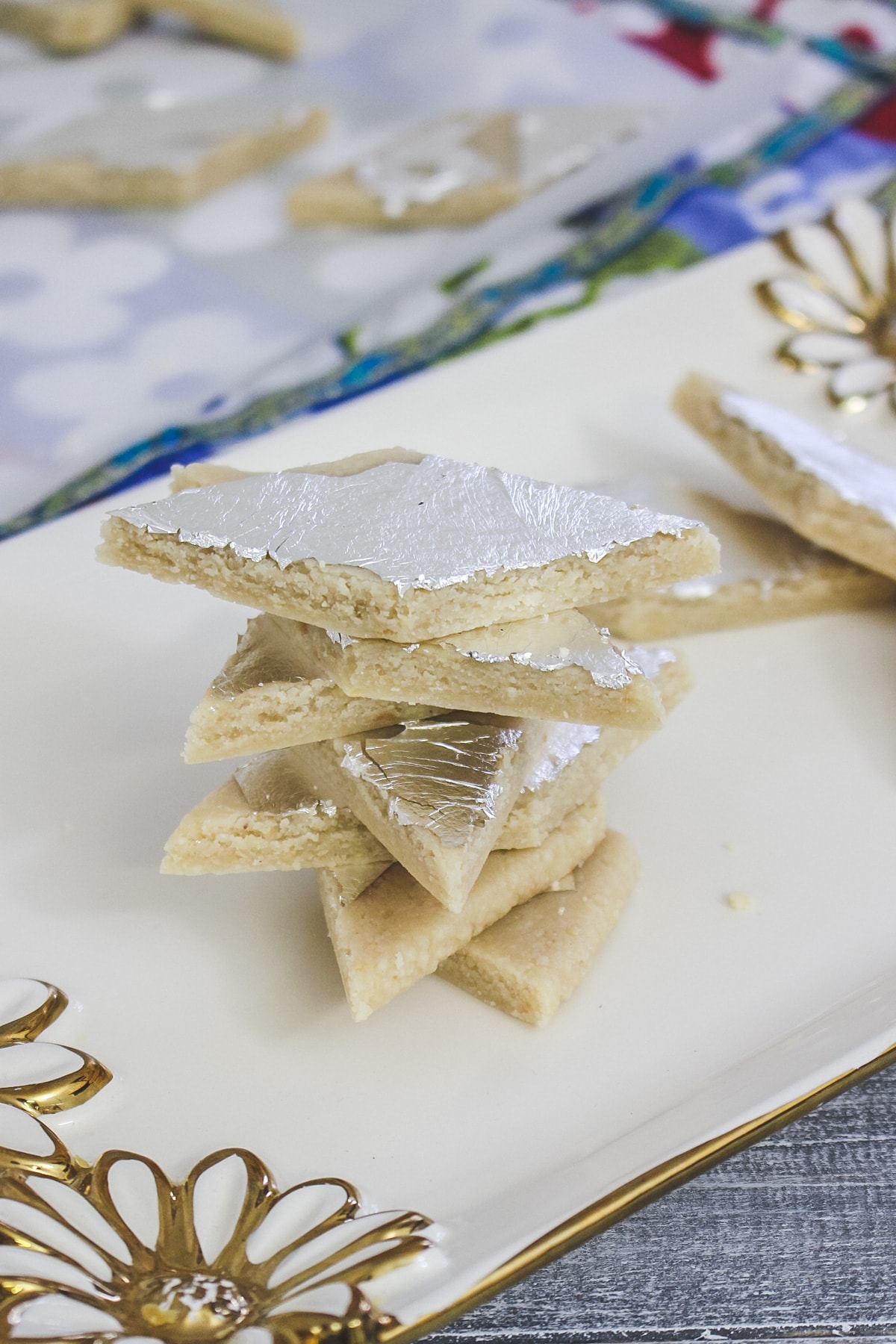 Stack of kaju katli in a gold flower decorated plate.