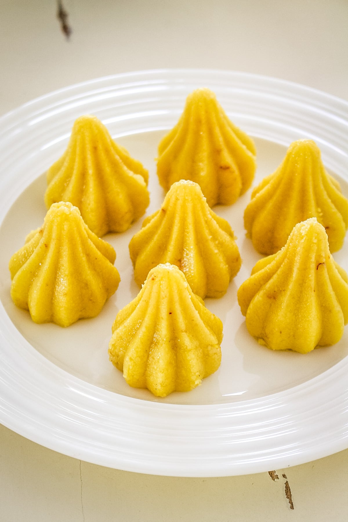 7 modak peda arranged on a white plate