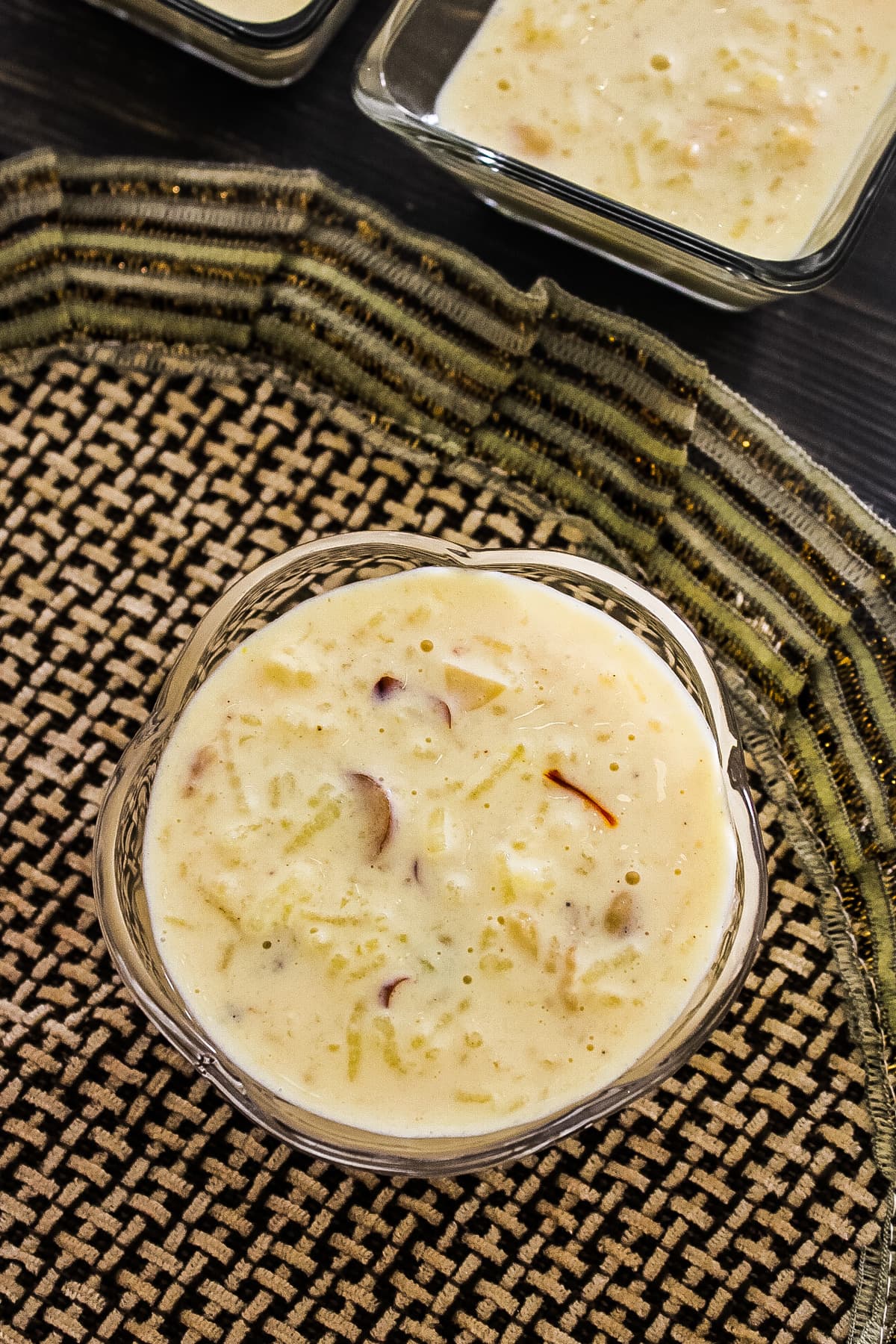 condensed milk kheer in a bowl with 2 square bowls in the back