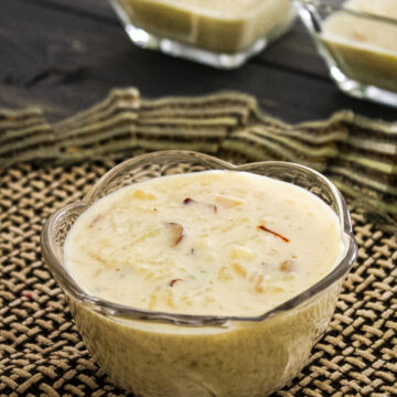 kheer in a bowl with decorative napkin underneath and 2 bowls of kheer in the back