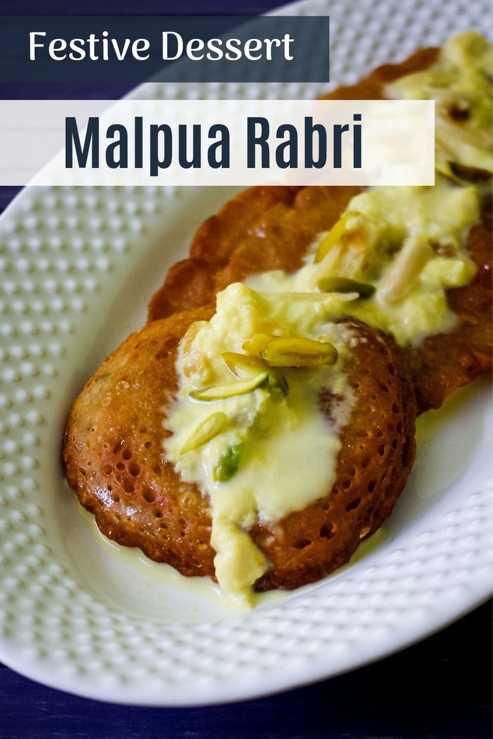 malpua topped with rabdi in a white plate and text on top of the image for pinterest