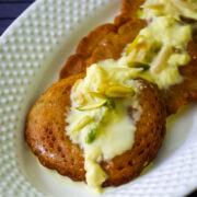 3 malpua in a plate and topped with rabdi and garnish with nuts