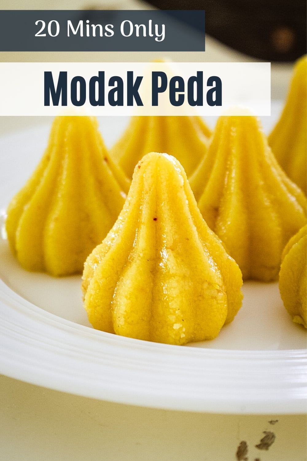 Modak peda on a plate with text on top says 20 mins only modak peda.