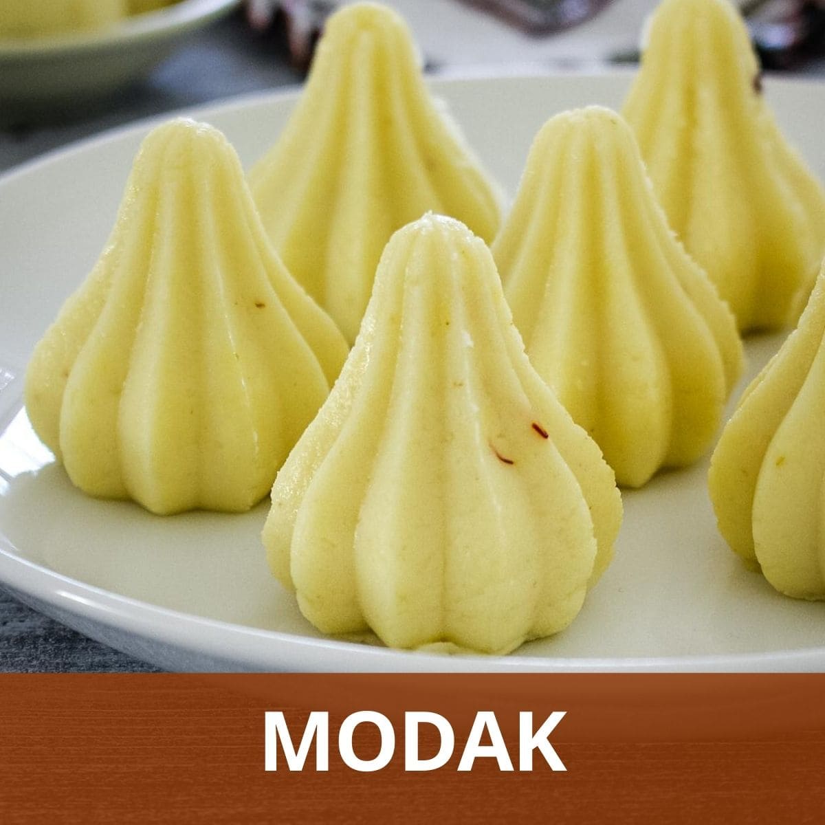 Modak arranged on a plate with text "modak" at the bottom with light red background