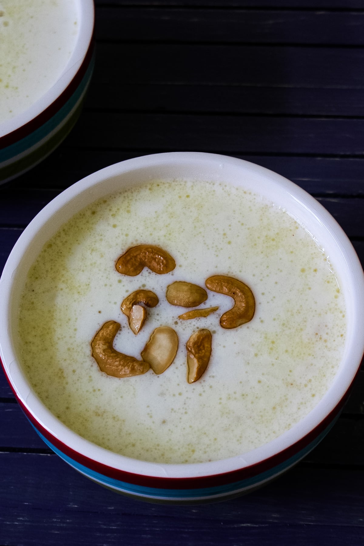 Close up image of paal payasam in a bowl with garnish of fried cashews.