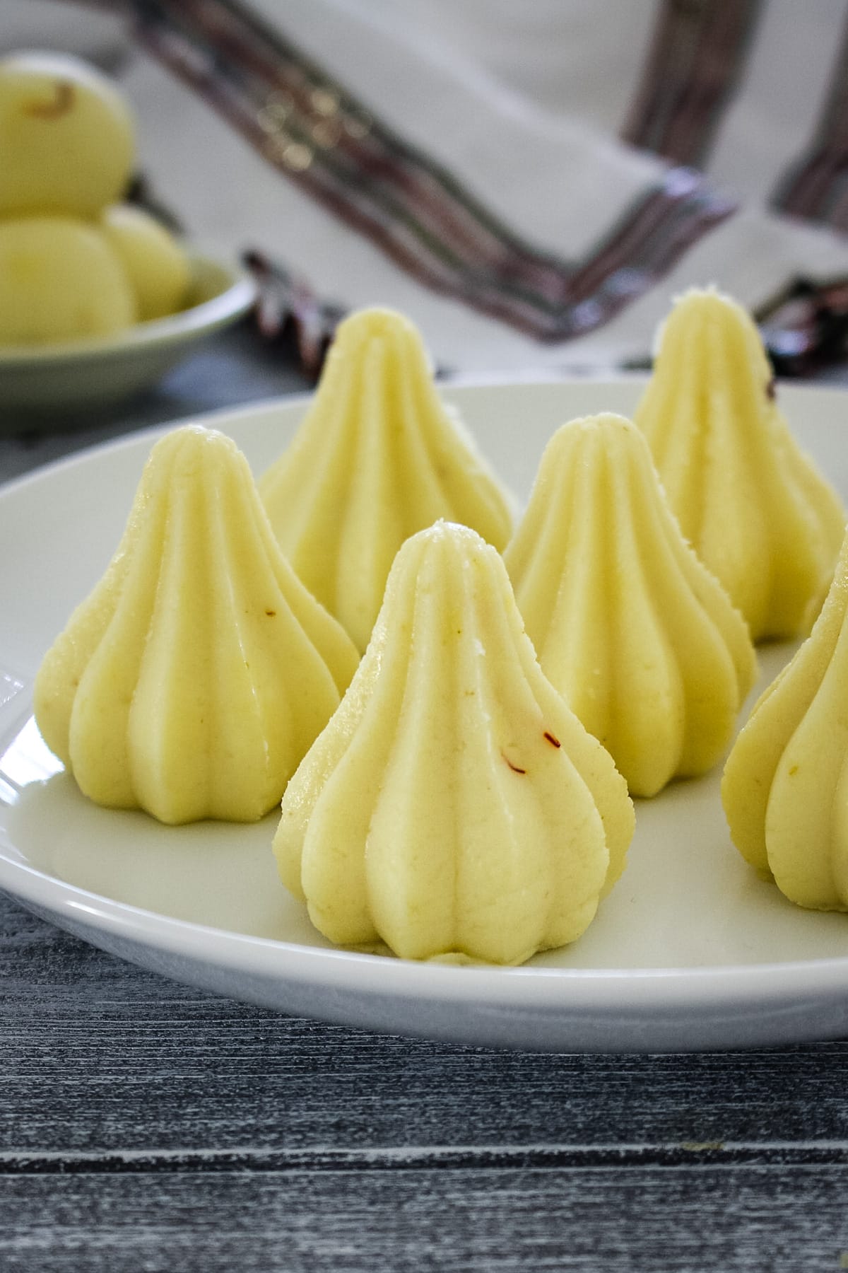 5 malai modak arranged on a plate with ladoo on the back side