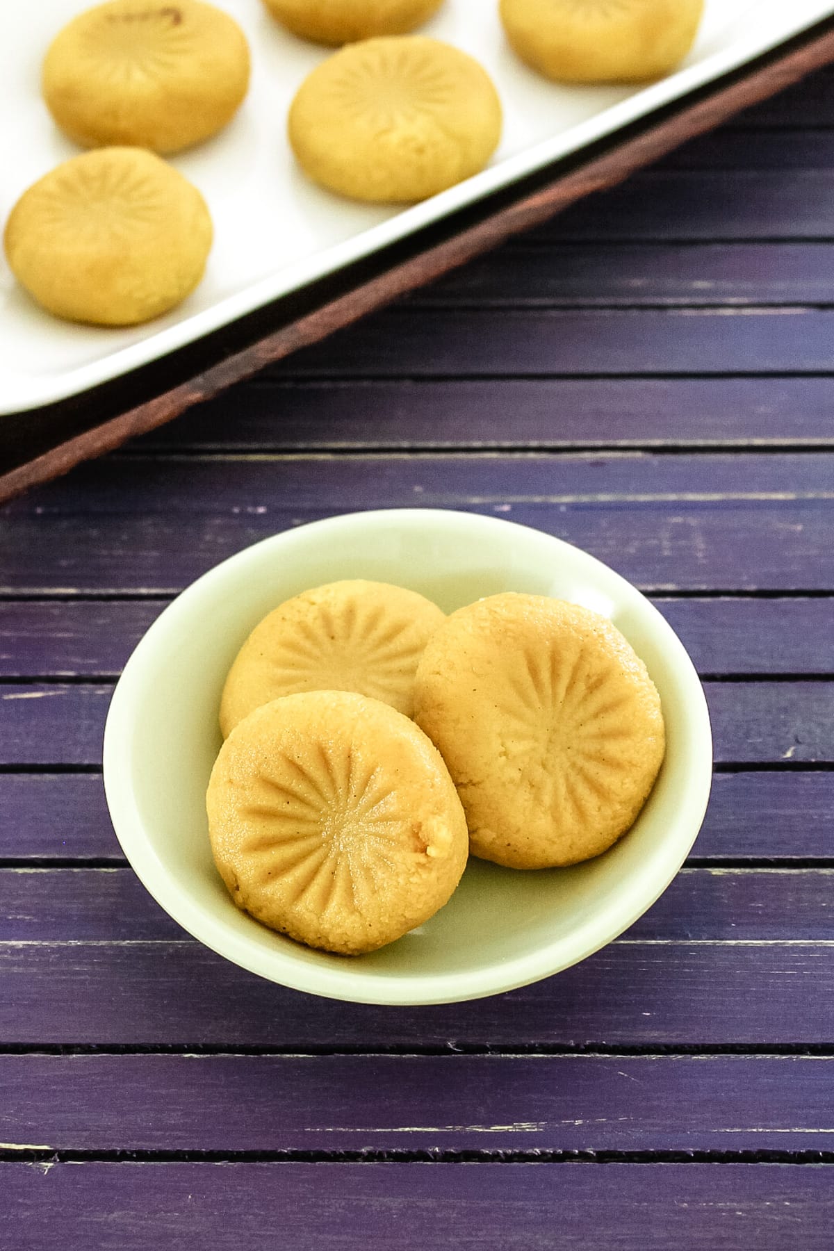 3 peda in a small plate with more peda served in large platter in the back