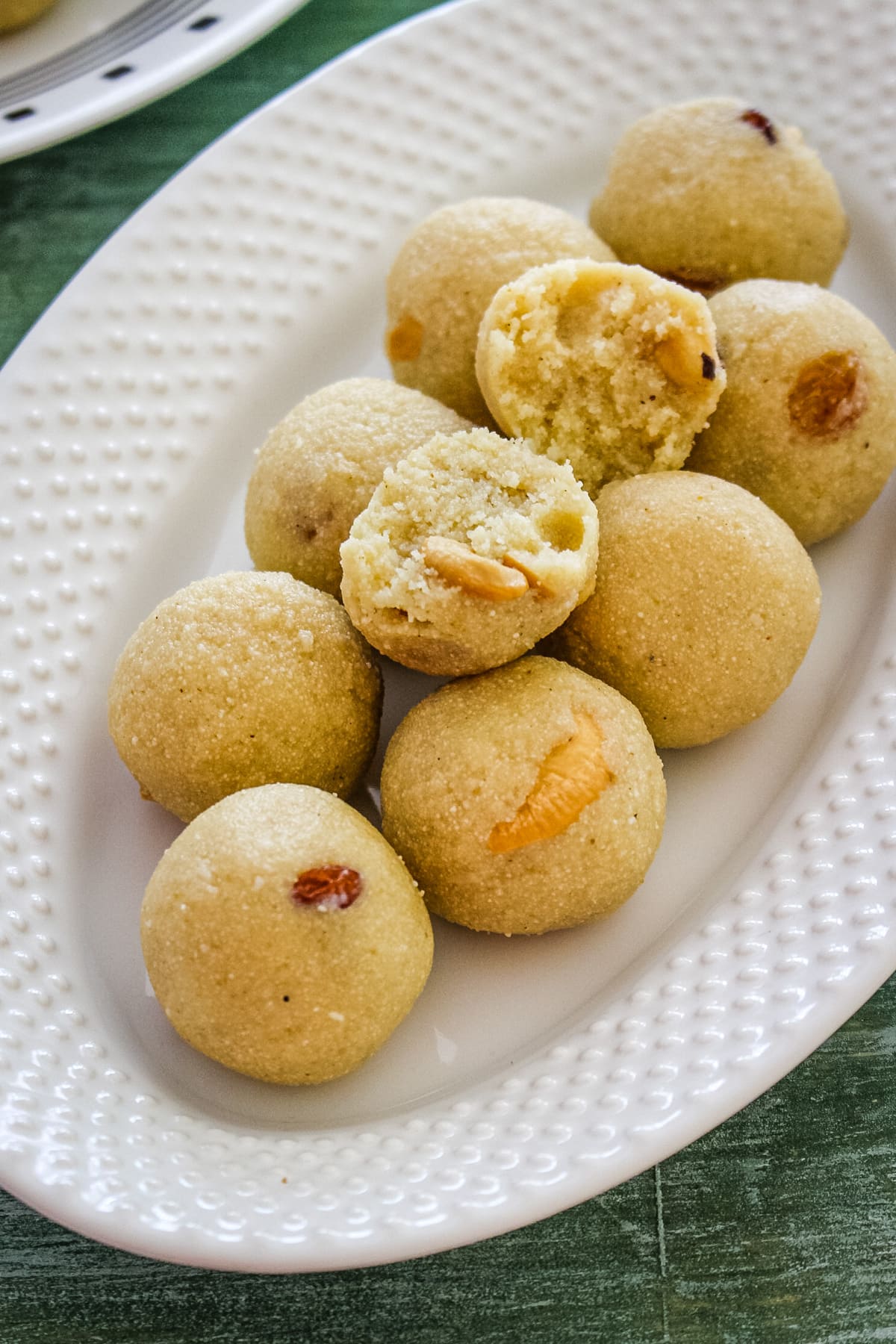 Top view of rava ladoo in oval plate with one laddu cut into half