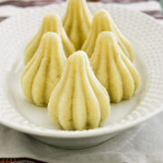 6 modaks arranged on a white oval plate with napkin under the plate