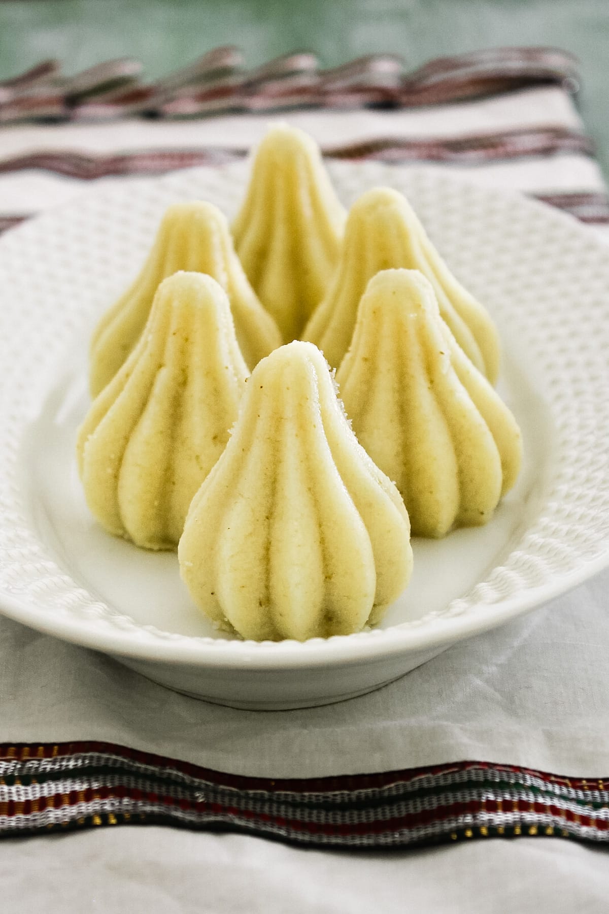 6 modaks arranged on a white oval plate with napkin under the plate