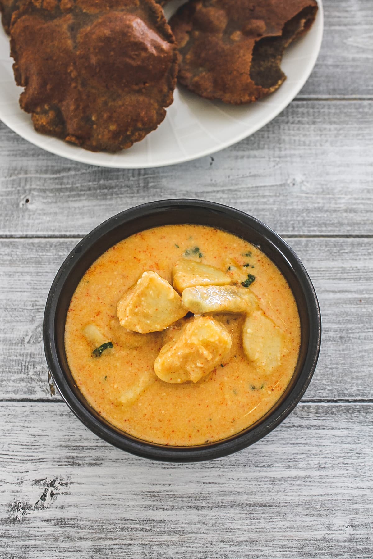 dahi arbi in a bowl with side of kuttu puri