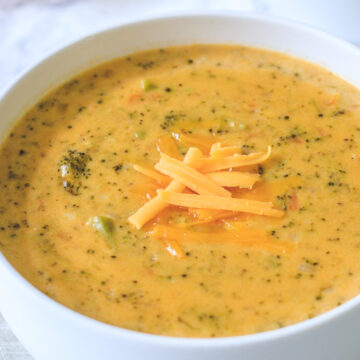 Close up of broccoli cheddar soup in a white bowl with cheese garnish