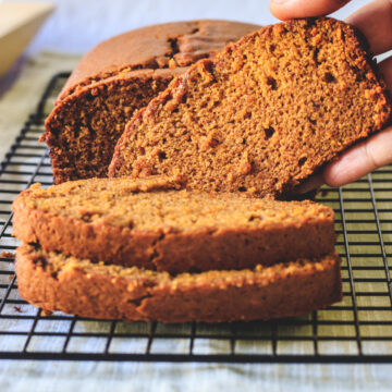 pumpkin bread on a rack lifting one slice ready to eat