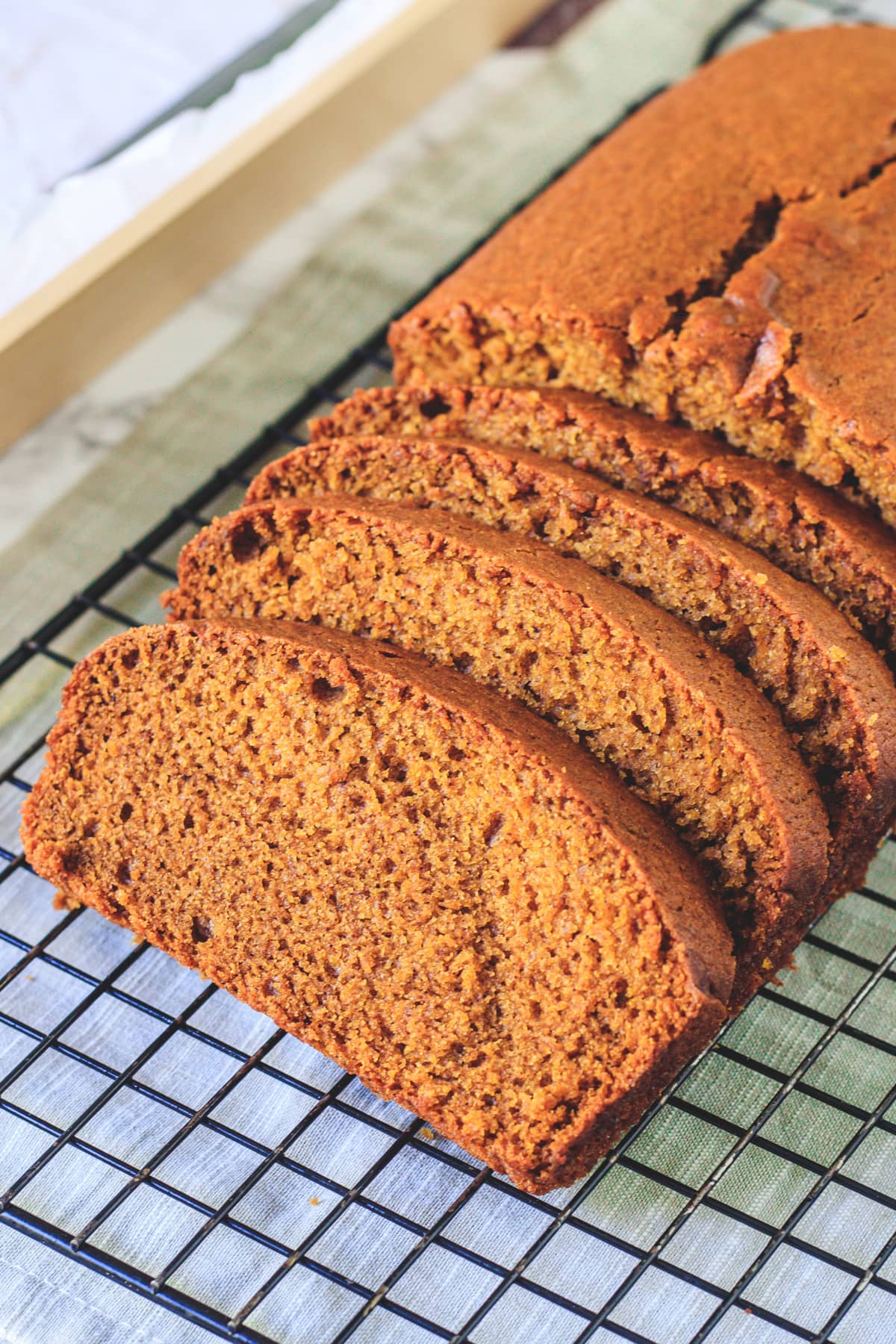 slices of eggless pumpkin bread on a wire rack with napkin underneath.