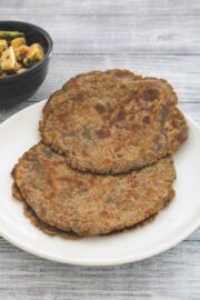 kuttu paratha in a white plate with suran sabzi on side.