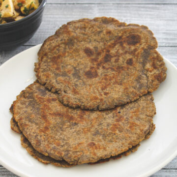 kuttu paratha in a white plate with suran sabzi on side.