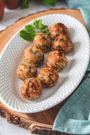 Sabudana vada in an oval plate with garnish of cilantro on a wooden board.