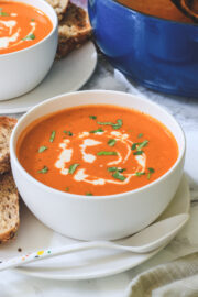 Roasted red pepper gouda soup in a bowl with side of bread.