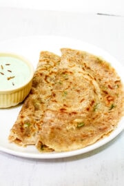 2 sabudana dosa in a white plate with coconut chutney in small bowl on the side