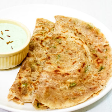 2 sabudana dosa in a white plate with coconut chutney in small bowl on the side