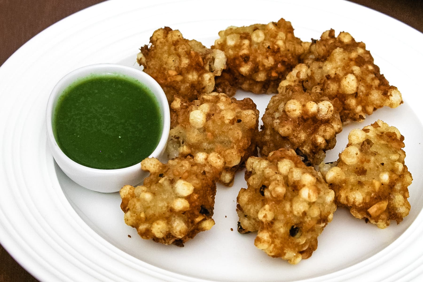 Close up of sabudana pakoda in a plate with green chutney dipping sauce