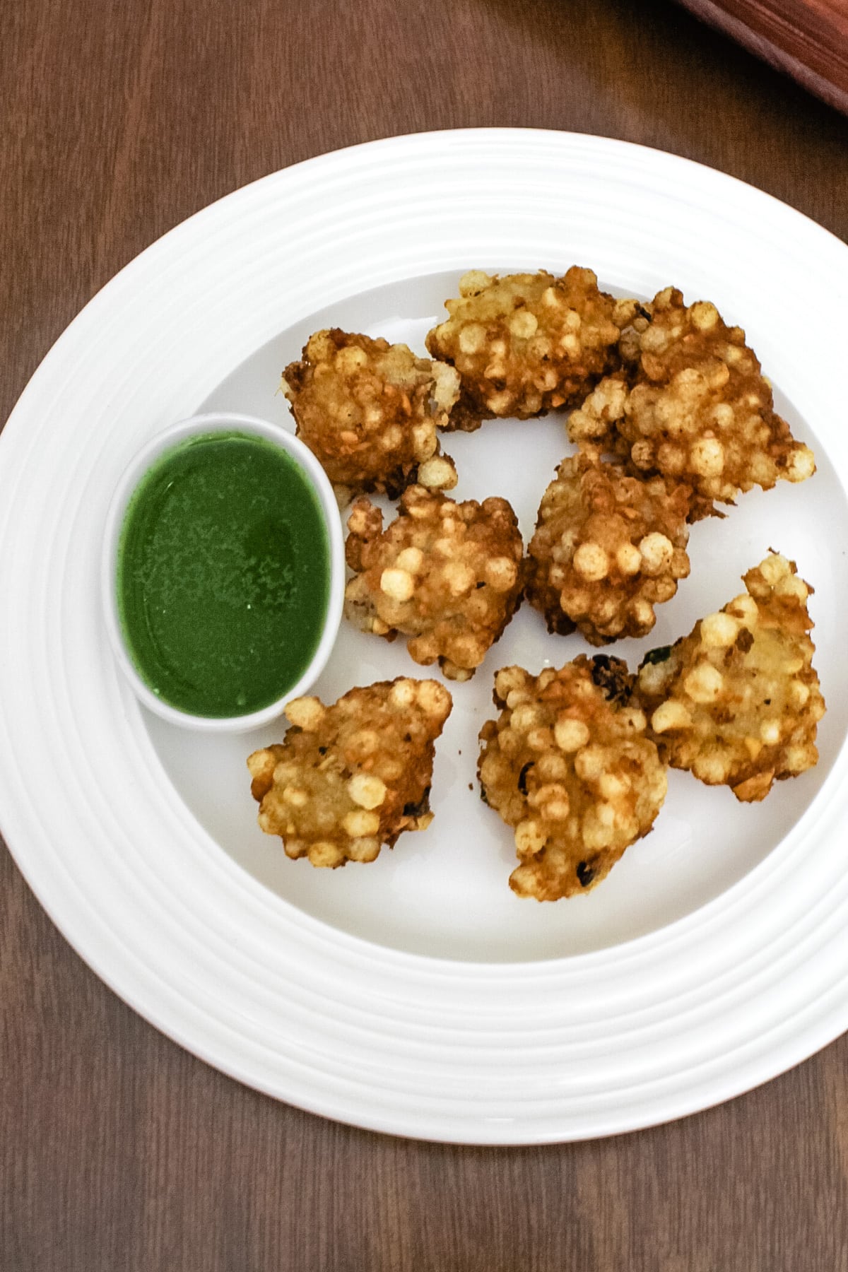 sabudana pakoda on a plate with side of green chutney