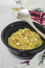 sweet potato halwa in a black bowl with a steel spoon rested on the bowl.