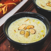 Close up of sweet potato kheer in a black bowl topped with fried nuts.