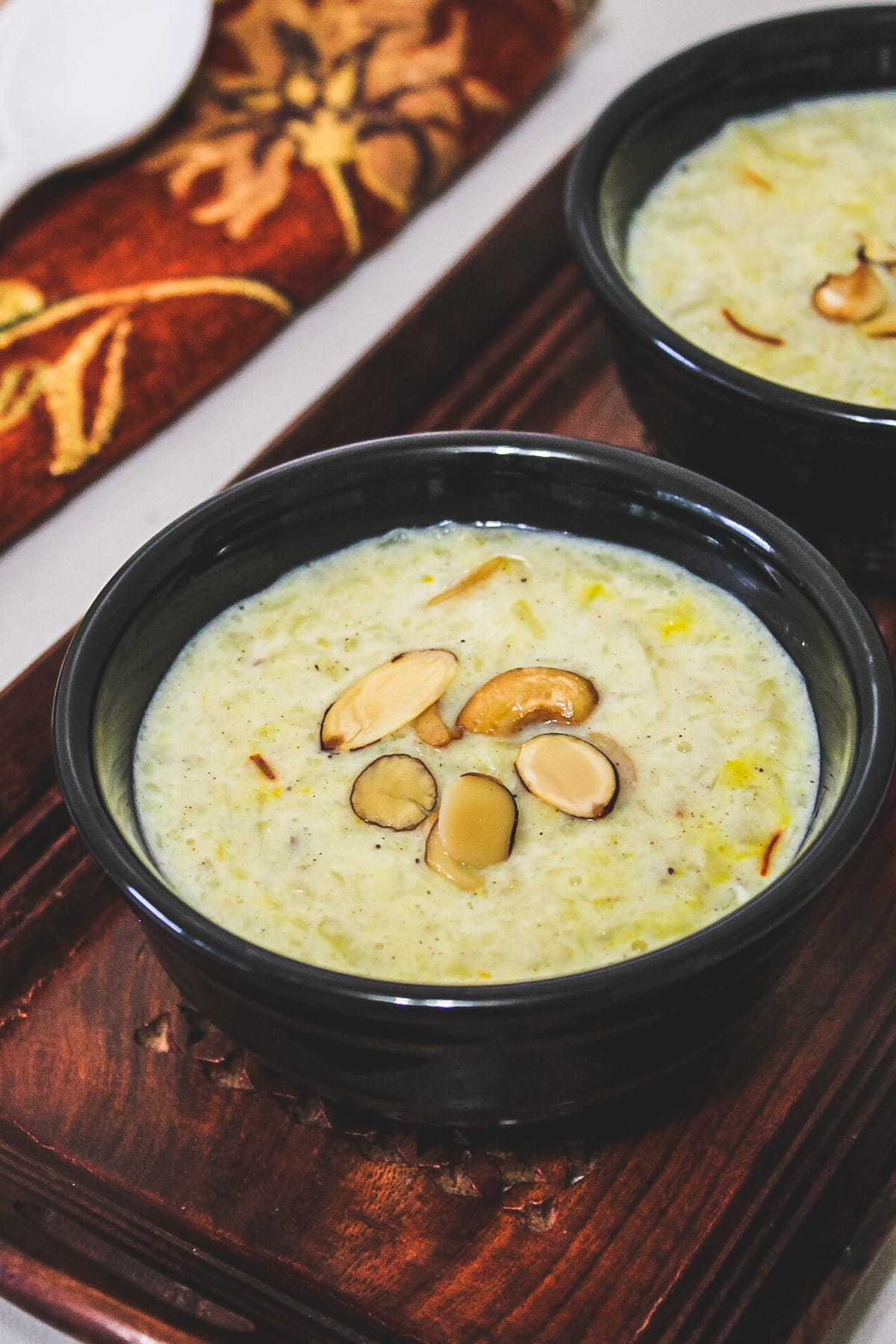 Close up of sweet potato kheer in a black bowl topped with fried nuts.