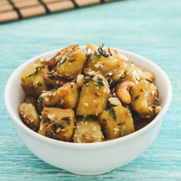 Sweet potato sabzi in a white bowl with blue background