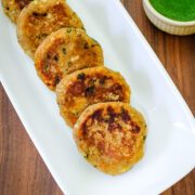 5 sweet potato tikki arranged in a plate with cilantro chutney on side