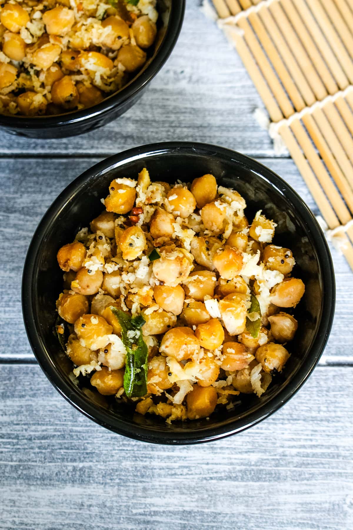 Chickpea sundal in 2 black bowls.