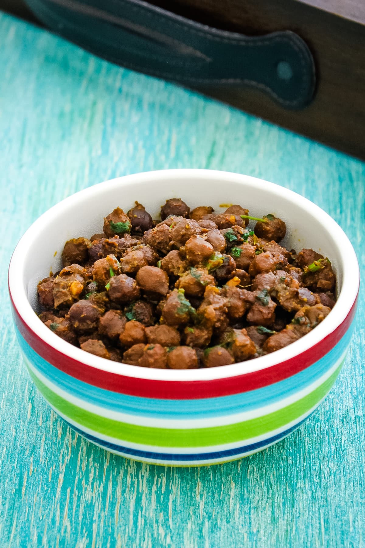 Dry chana in a bowl with wooden tray in the back,