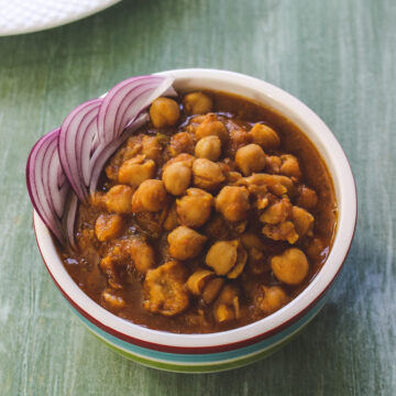 Instant pot chana masala garnished with sliced onions, served with paratha.