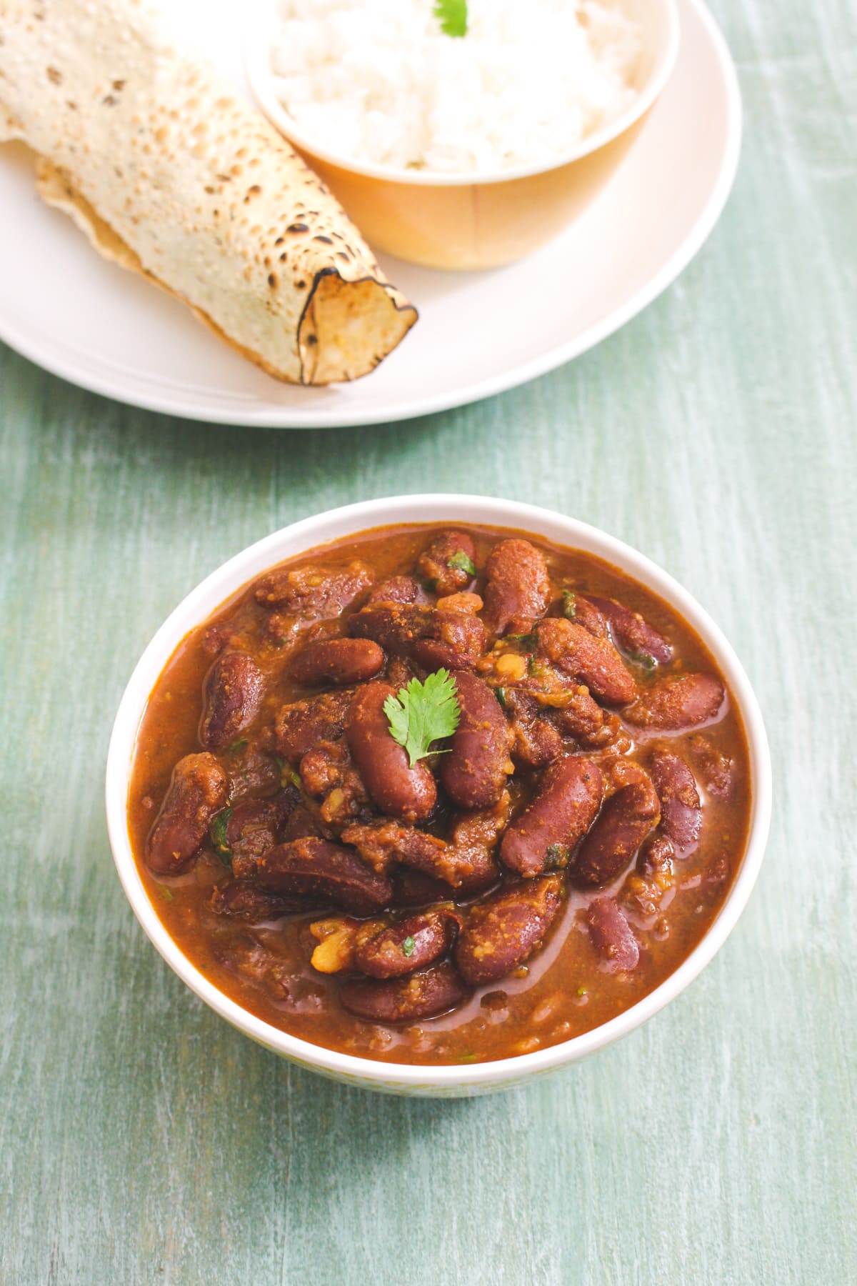 Top view of rajma in a bowl served with papad and rice.