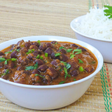 Kala chana curry served in a bowl with a bowl of rice in the back.