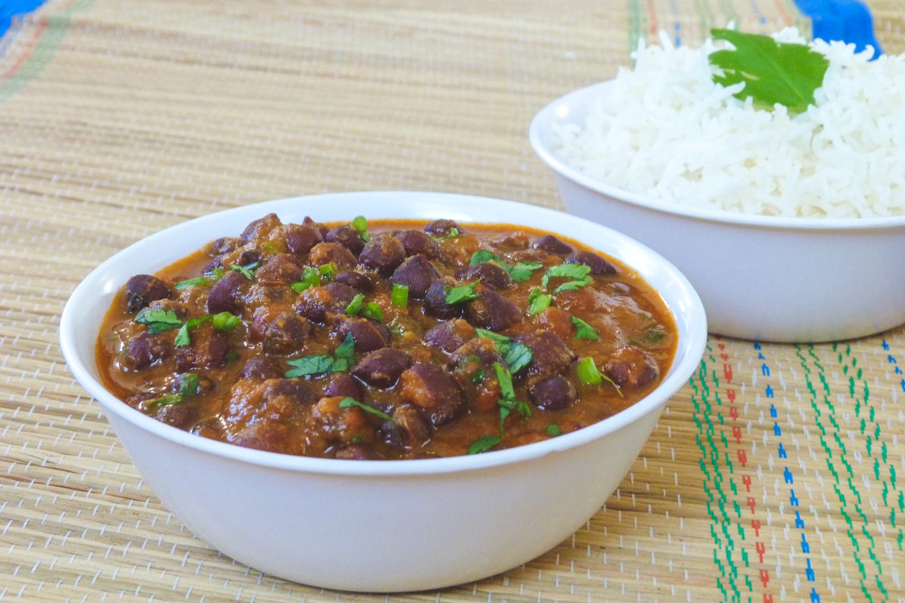 Kala chana curry served in a bowl with a bowl of rice in the back.