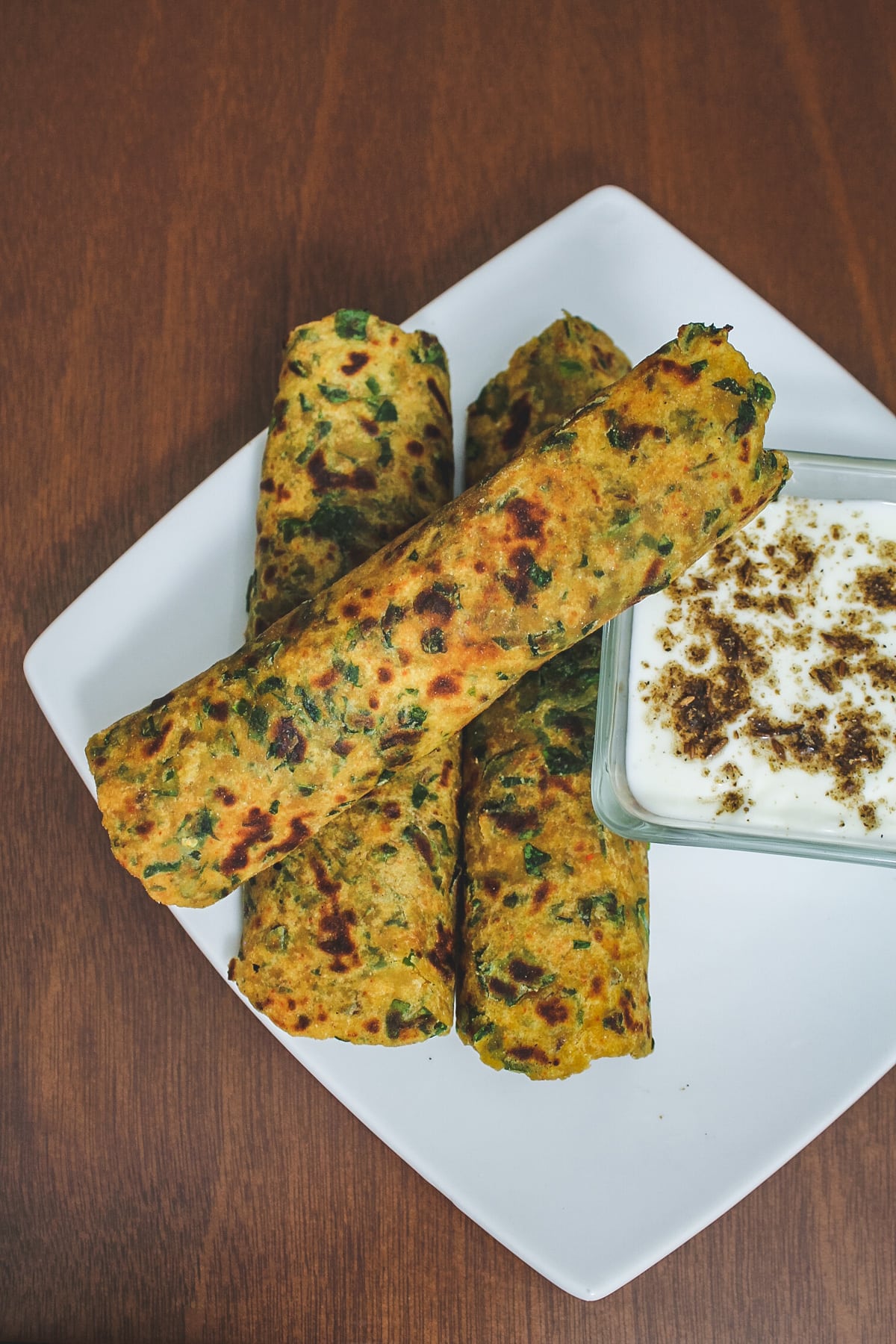 Top view of 3 methi paratha served with yogurt.